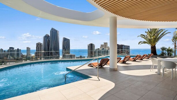 Ein Pool auf dem Dach mit Blick auf die Stadt, Liegestühle und eine Pergola.