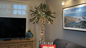 A living room with a television, a Christmas tree, a sofa, and a framed picture on the wall.