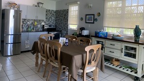 A modern kitchen with a dining area, featuring a stainless steel refrigerator, a stove, and a tiled backsplash.