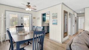 A spacious living area with a dining table, chairs, a ceiling fan, and a sofa.