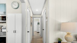 A hallway with white cabinets, a clock, a lamp, and a small plant.