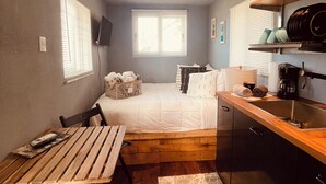 A compact room with a bed, a small kitchenette, a dining area, and a window providing natural light. - Tiny house on an acre with ocean view and private infinity pool.  (Vieques)