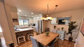 A modern kitchen with a central island, wooden dining table, and chairs.
