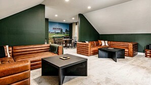 Un loft amplio con techos altos y techo inclinado. Cuenta con sofás de cuero, una mesa de centro y un comedor con vista a un campo de golf.