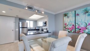 A modern kitchen with a central island, white cabinetry, and a large window.