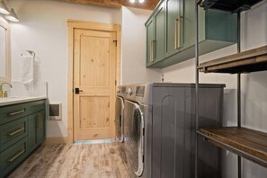 A laundry room with a washing machine, a dryer, and a wooden door.
