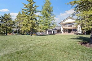 A large, two-story house with a spacious front yard and a garage. - New! Modern Cabin w/fireplace/hot tub/sleeps 12 (Donnelly)