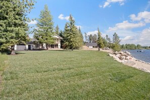 A house with a large lawn and a lake view.