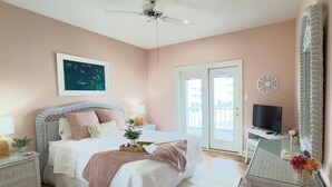 A bedroom with a bed, bedside tables, a television, and a large mirror. - Oceanfront/Zero Steps to Beach/Views/4BR (Gulf Shores)