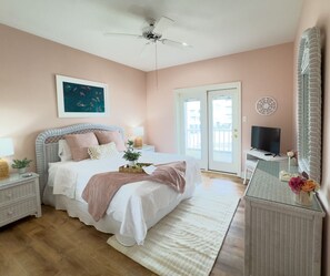 A bedroom with a bed, bedside tables, a television, and a large mirror. - Oceanfront/Zero Steps to Beach/Views/4BR (Gulf Shores)