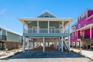 A beachfront property with a covered porch, multiple levels, and a distinctive color scheme.