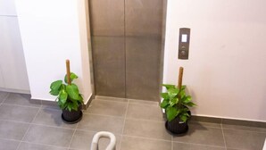 An elevator with a metallic finish, flanked by two potted plants. - The Crown Hotel Klia (Sepang)