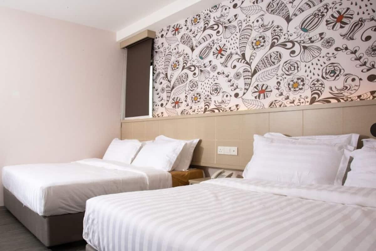 Ein Hotelzimmer mit zwei Betten, einer strukturierten Wand und einem kleinen Nachttisch mit Telefon.