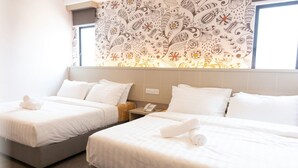 A hotel room with two beds, each with white linens and towels, a bedside table with a phone, and a patterned wall above the beds. - The Crown Hotel Klia (Sepang)