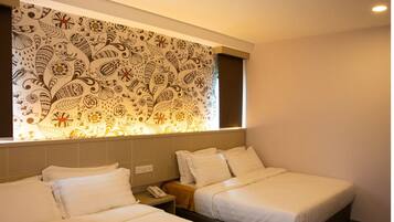 A hotel room with two beds, a patterned wall, and a window with curtains.