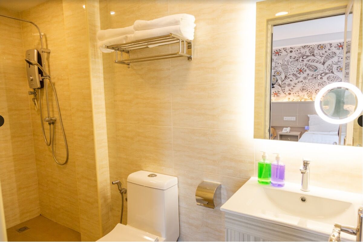 A bathroom with a shower, toilet, towel rack, sink, and a mirror with a round light.