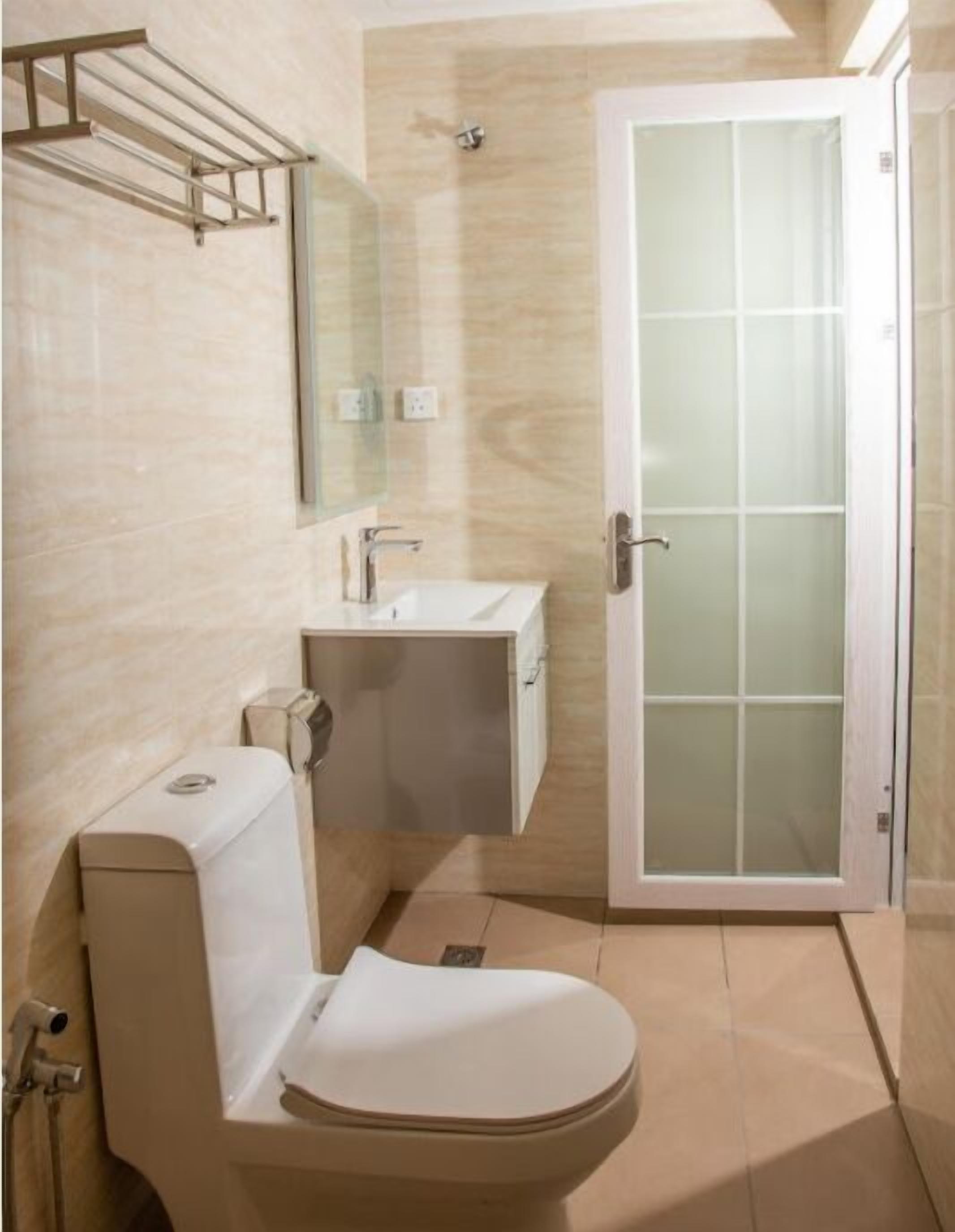 A modern bathroom with a toilet, sink, and glass shower door.
