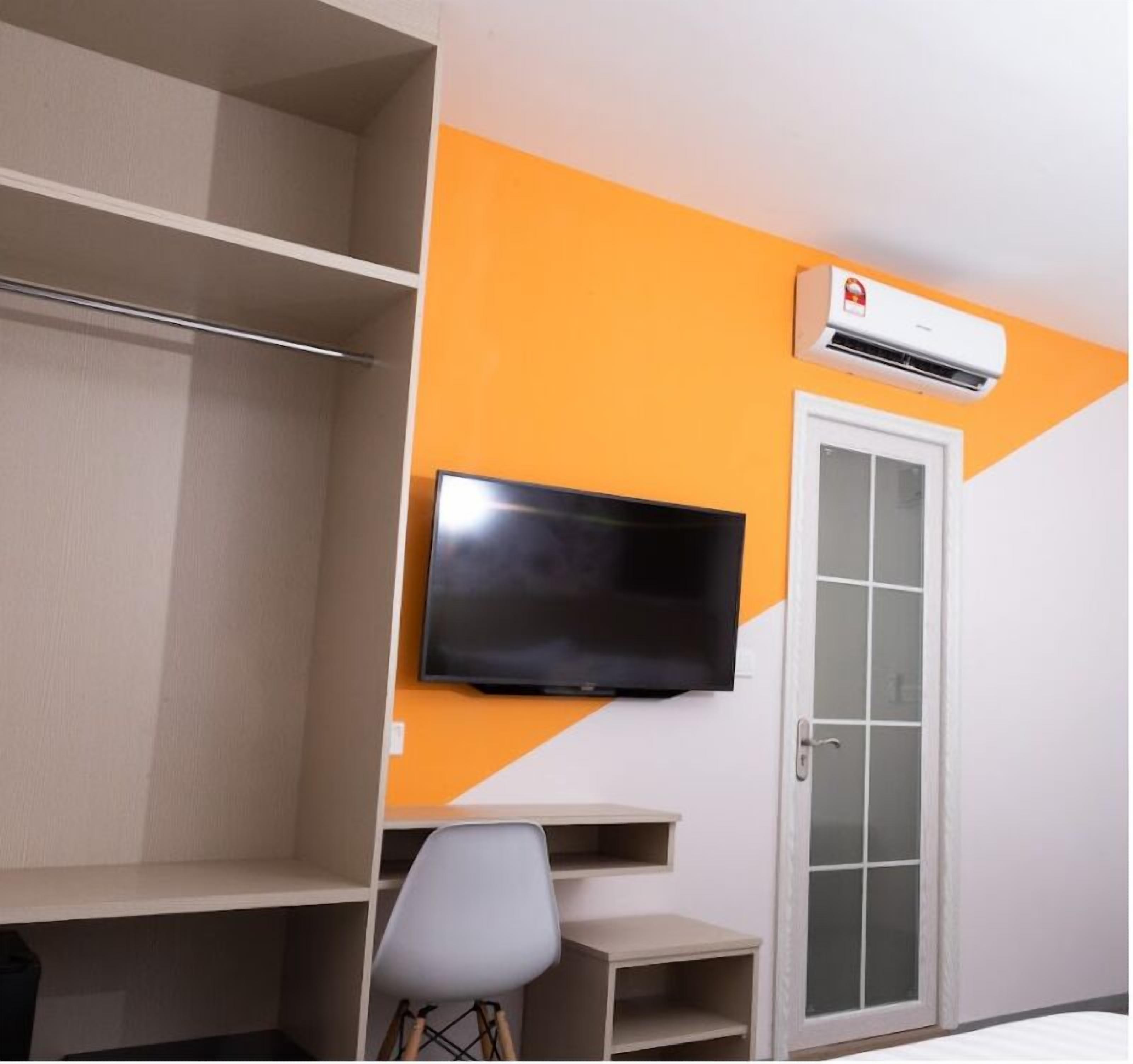 A room with a television mounted on the wall, a white door, and an air conditioning unit.