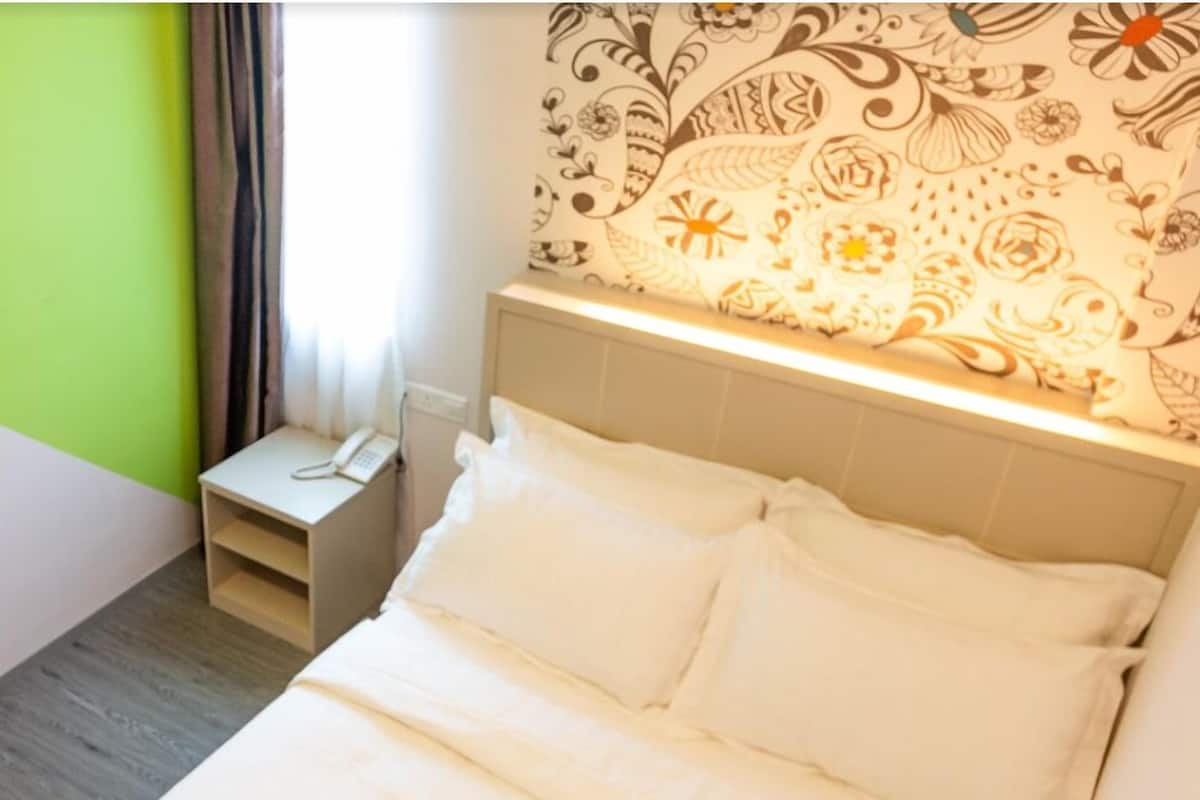 Ein Hotelzimmer mit einem Bett, einem Nachttisch mit Telefon und einer Wand mit Muster.