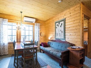 Un intérieur en bois comprenant une table à manger, des chaises, un canapé et une petite table d’appoint en bois.