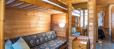 Un interno accogliente di una baita con una panca di legno, una scrivania e un piccolo tavolo.