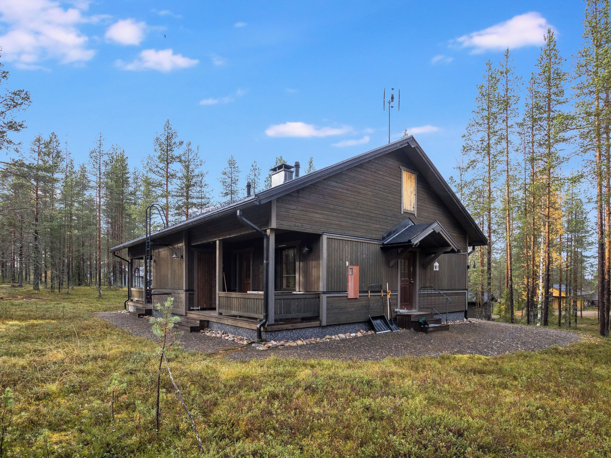 Mökki, jossa on kuisti, savupiippu ja pieni terassi.