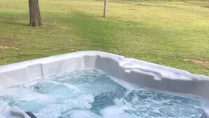 Un jacuzzi con interior blanco y exterior negro, rodeado de césped.