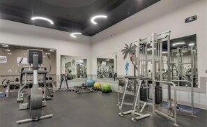 A gym with exercise equipment, mirrors, and a variety of weights.