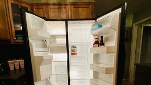 A kitchen with a refrigerator, wooden cabinets, and a wooden floor. - **cozy country** *stargazing acre* (Franklinton)