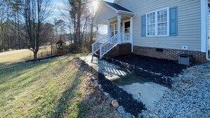 A two-story house with a covered porch, a brick foundation, and a small garden area. - **cozy country** *stargazing acre* (Franklinton)