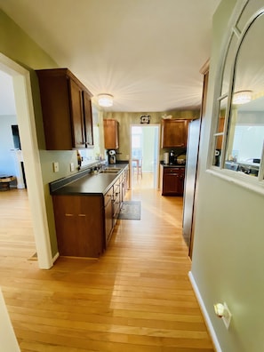 A spacious kitchen with wooden cabinets, a central island, and a view into the dining area. - **cozy country** *stargazing acre* (Franklinton)