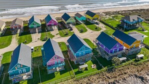 A coastal residential area with colorful houses, a beach, and a clear view of the ocean. - ☀ Tranquil beach! 100ft to Beach ~ Ocean Views, Pets  (Galveston)