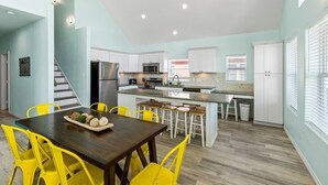 A modern kitchen with white cabinets, a central island, and yellow chairs. - ☀ Tranquil beach! 100ft to Beach ~ Ocean Views, Pets  (Galveston)