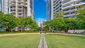 A modern urban courtyard with a central pathway, surrounded by high-rise buildings and lush greenery. - Surfers Paradise Getaway: Amazing Resort Amenities (Surfers Paradise)