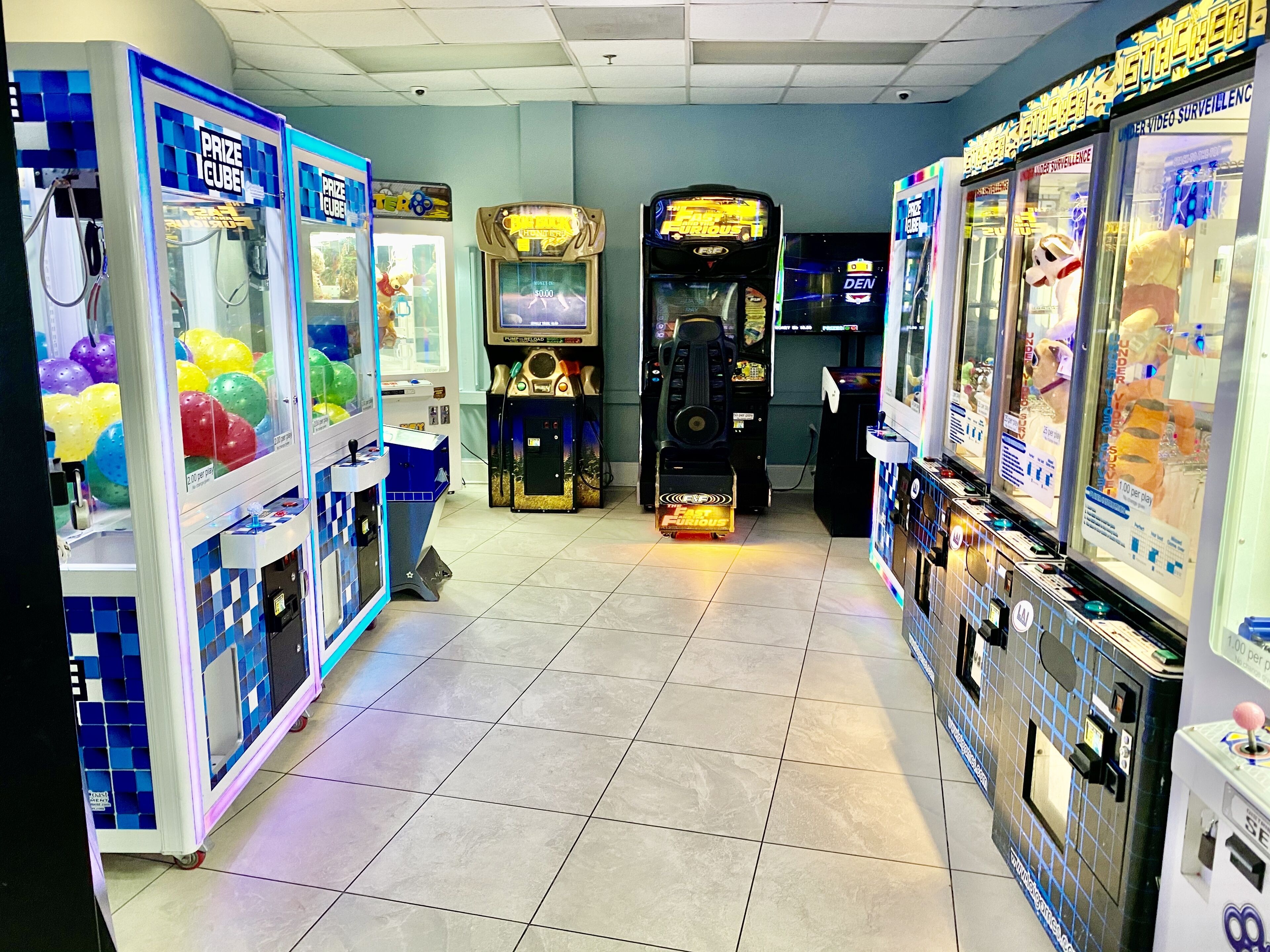 Una hilera de máquinas de arcade con juegos de premios en cubos y una máquina de canje de tickets.