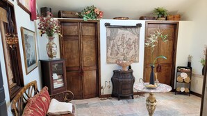 Quarto aconchegante com guarda-roupa de madeira, sofá de vime, piso de mármore e uma mesa decorativa com um vaso.