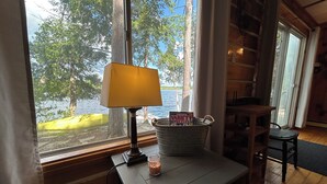 Een knus interieur van een blokhut met een houten tafel, een lamp, een kaars en een emmer met een puzzelboek.