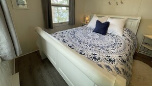 Een slaapkamer met een bed, een raam, een nachtkastje en decoraties aan de muur.