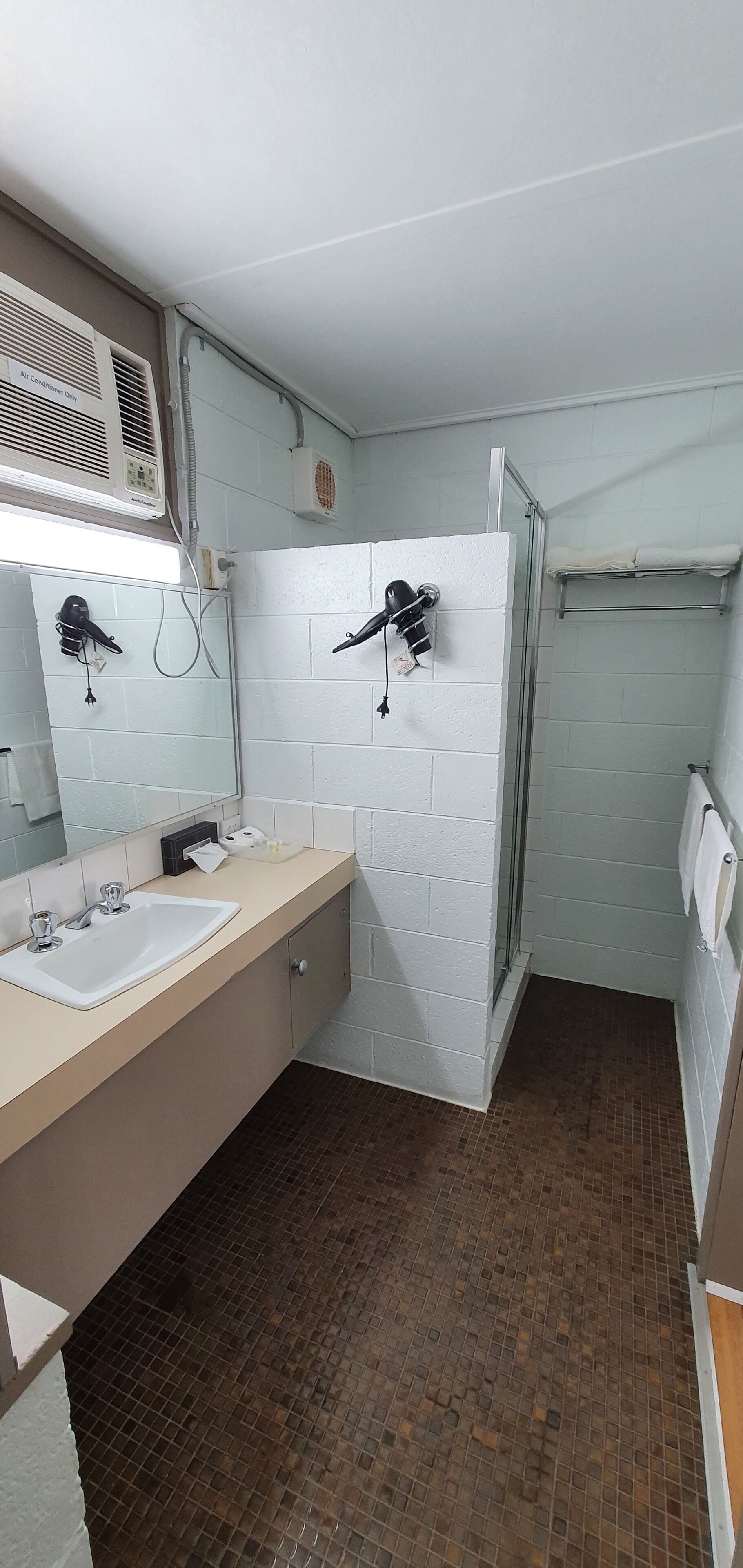 Une salle de bain avec deux lavabos, un miroir, un porte-serviettes et un espace douche.