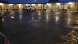 A parking lot with a white van parked in the center, surrounded by benches and potted plants. - Morwell Parkside Motel (Morwell)