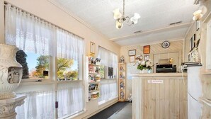 A room with large windows, a wooden reception desk, and a bookshelf filled with books and magazines. - Morwell Parkside Motel (Morwell)