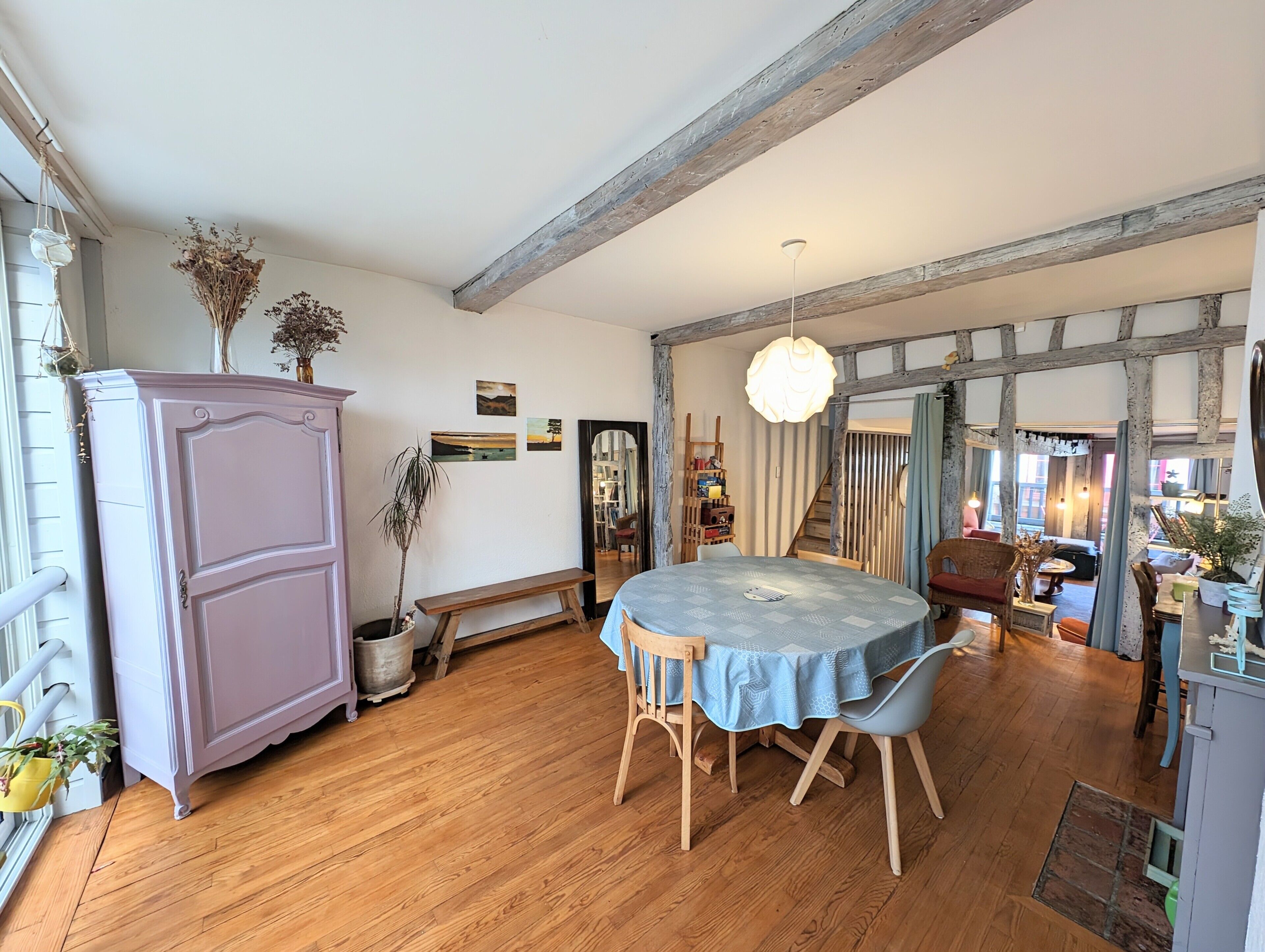A dining area with a round table, chairs, a bench, and a cabinet.