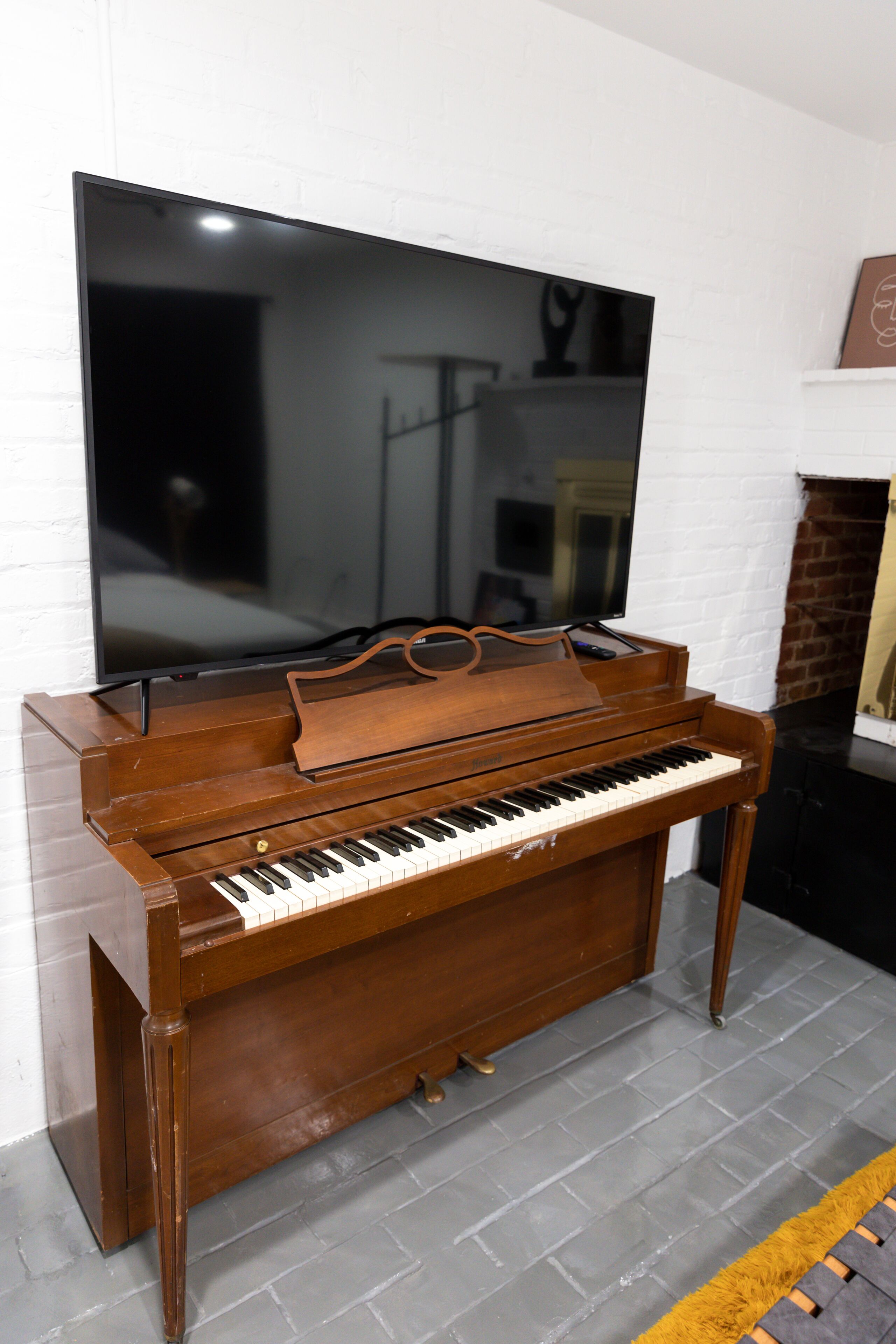 A grand piano in a room with a large flat-screen TV mounted on the wall.