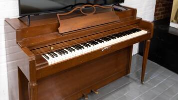 A grand piano in a room with a large flat-screen TV mounted on the wall.