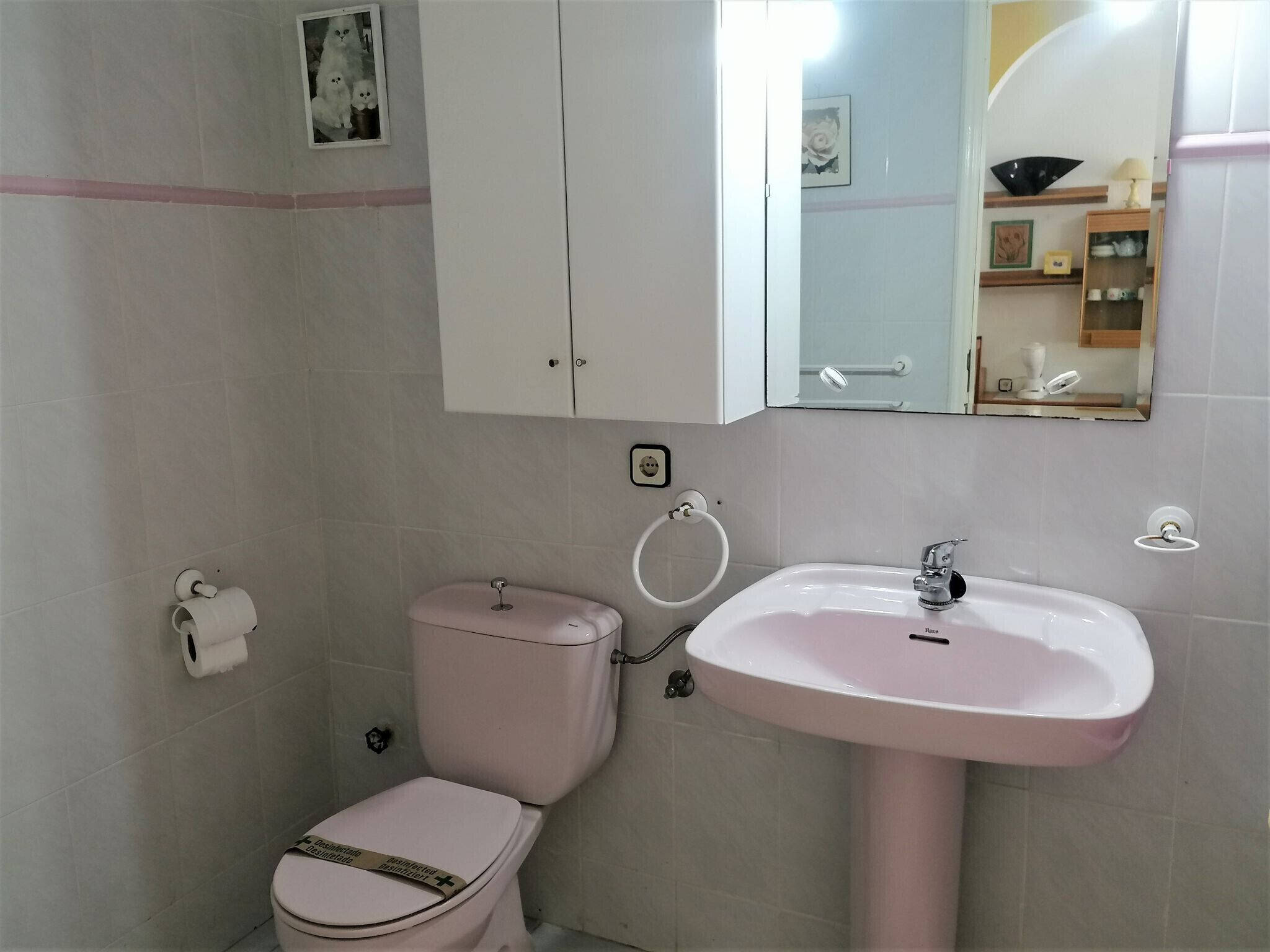 A bathroom with a toilet, sink, and cabinet.