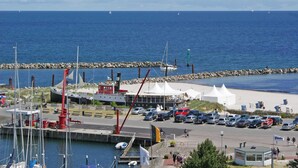 Una marina con barcos, un estacionamiento y una zona de playa con tiendas de campaña.