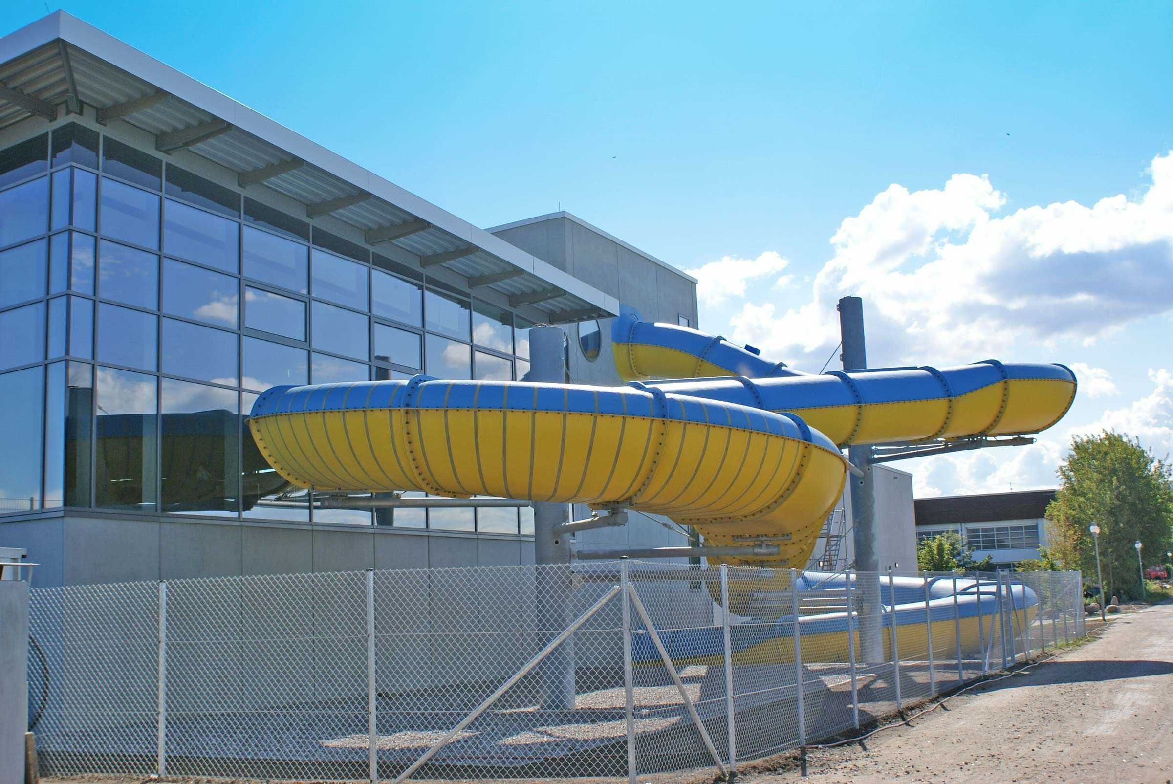A modern building with large windows and a water slide structure in front.