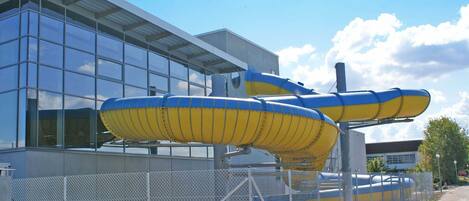 A modern building with large windows and a water slide structure in front.