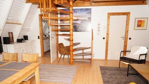 Acogedor dormitorio tipo loft con escalera de madera, zona de comedor y vistas al mar.