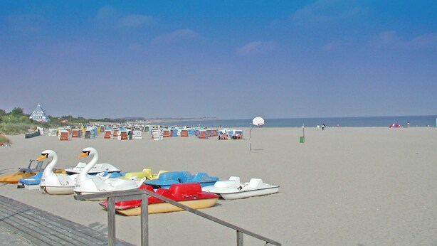 Una playa con varios barcos y una torre de salvavidas.